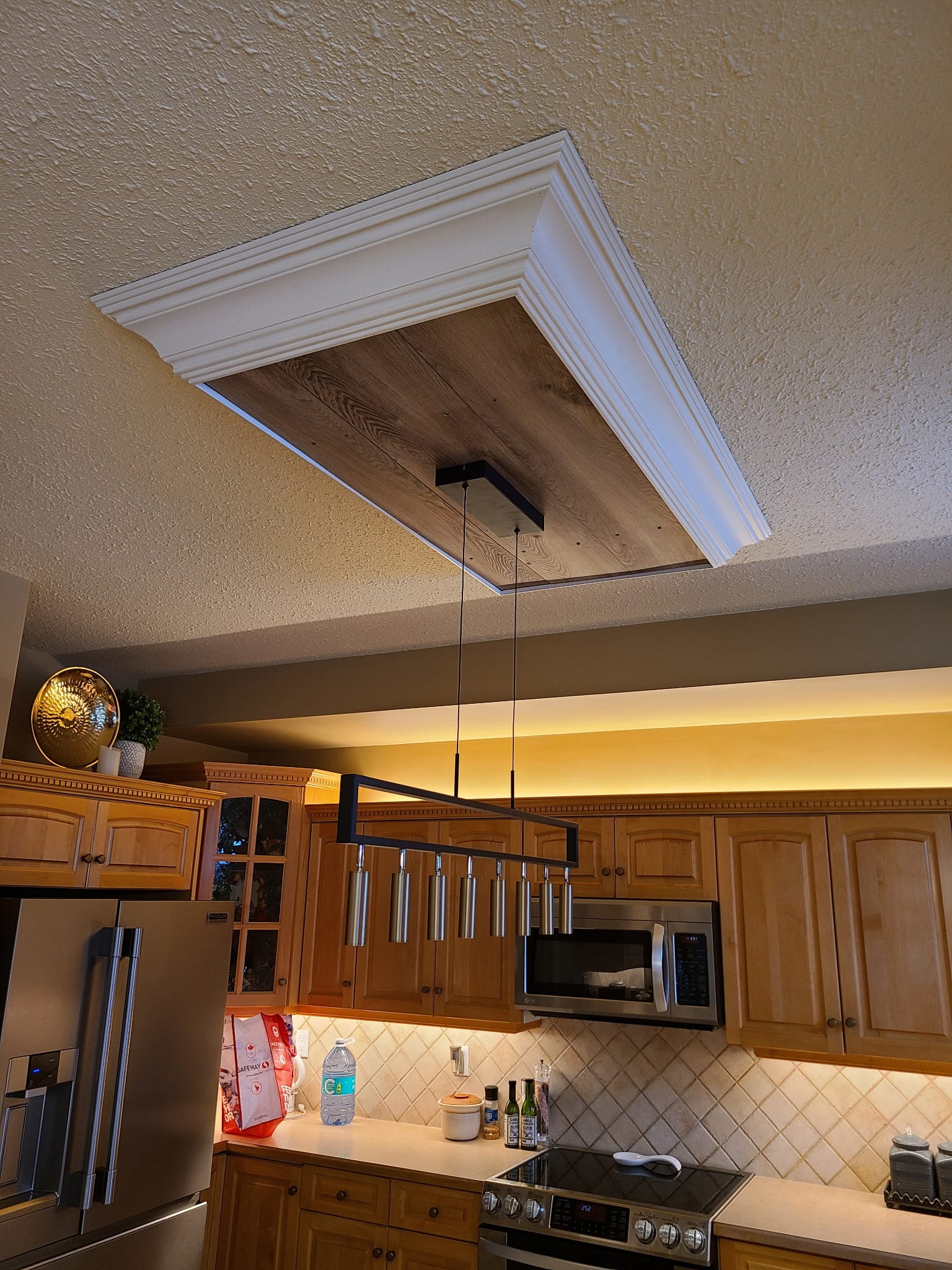 Custom kitchen with wood slat ceiling, linear pendant and recessed pot lighting in an Edmonton home by Call Paul Contracting
